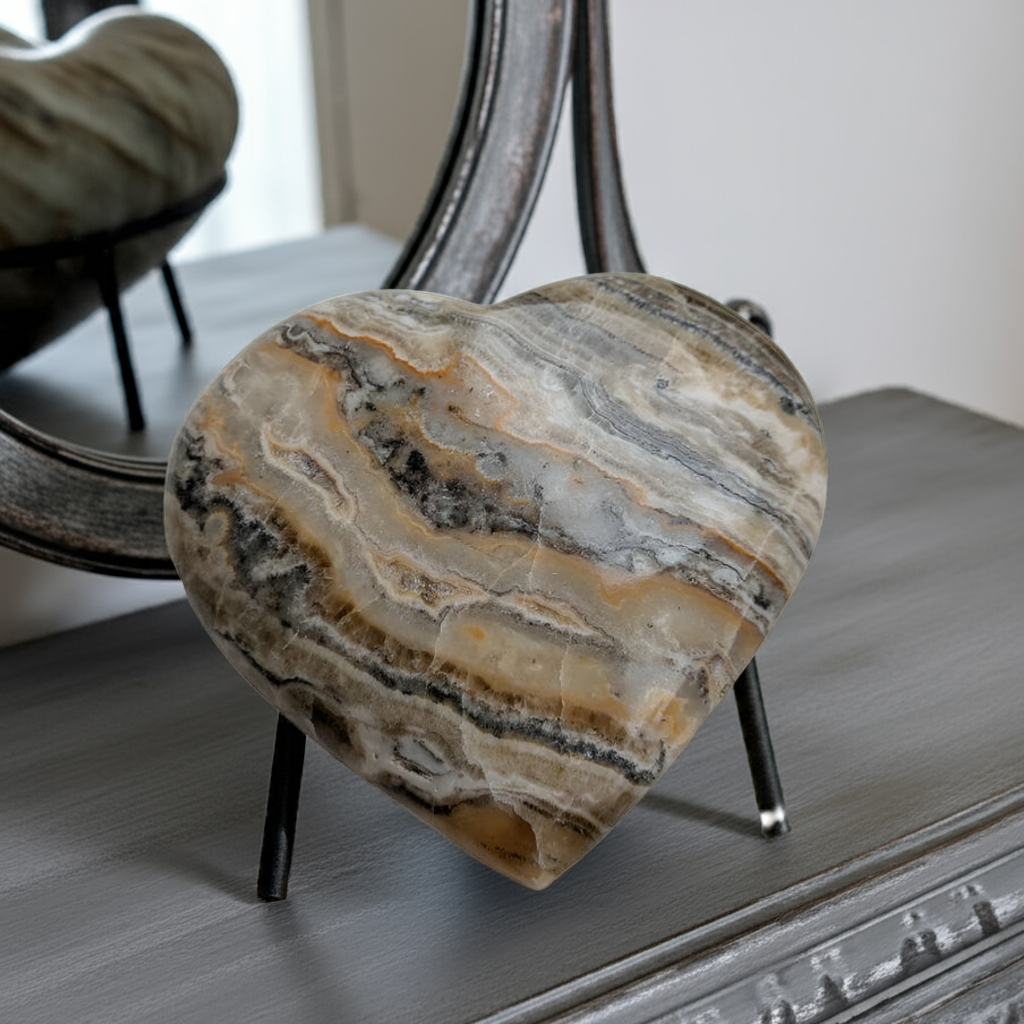  Bumblebee Calcite Heart crystal displayed on grey dresser with mirror reflection, showcasing golden honey bands and natural stone patterns for spiritual home decor