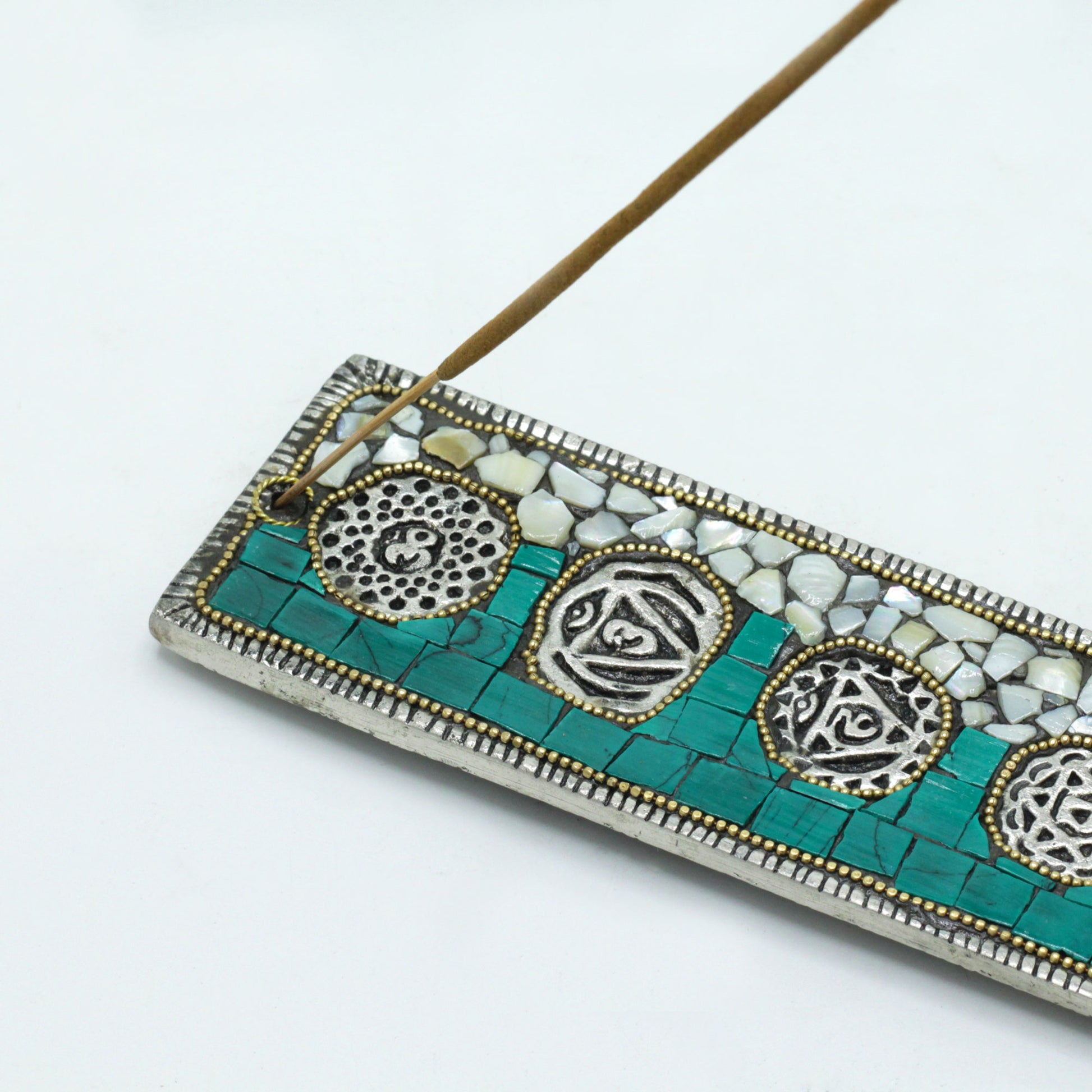 Close-up of chakra incense holder showing detailed mosaic work and chakra symbols